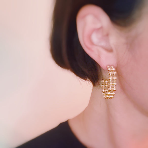 Gold-tone hoop earrings featuring a double layered ball chain design for a bold, textured look.