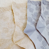 Set of two soft knit socks featuring an embossed flower pattern throughout, offering cozy texture and a subtle floral detail for everyday comfort with a delicate twist.