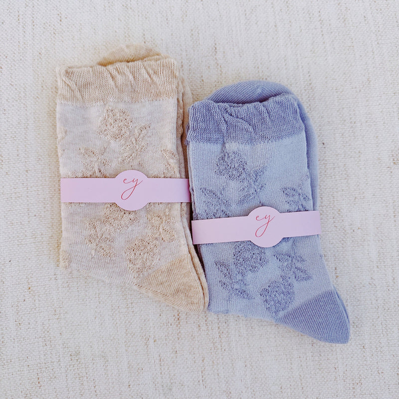 Set of two soft knit socks featuring an embossed flower pattern throughout, offering cozy texture and a subtle floral detail for everyday comfort with a delicate twist.
