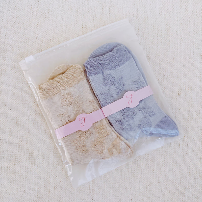 Set of two soft knit socks featuring an embossed flower pattern throughout, offering cozy texture and a subtle floral detail for everyday comfort with a delicate twist.