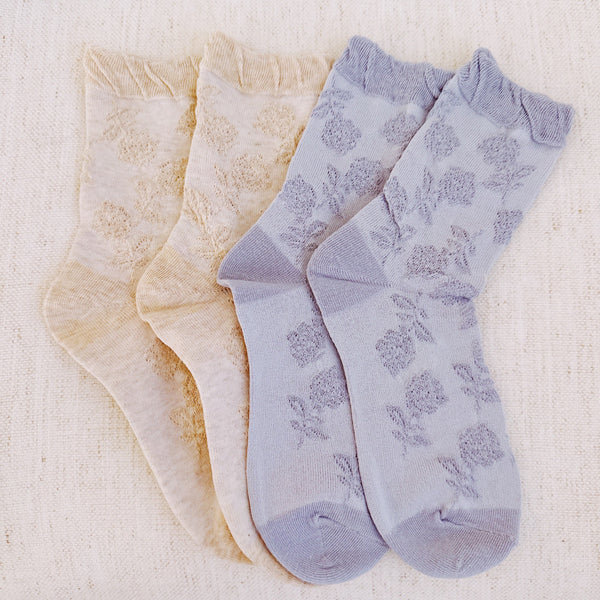 Set of two soft knit socks featuring an embossed flower pattern throughout, offering cozy texture and a subtle floral detail for everyday comfort with a delicate twist.