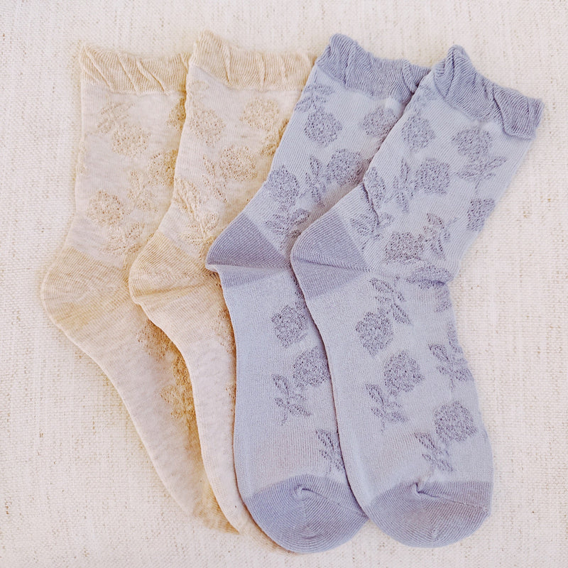 Set of two soft knit socks featuring an embossed flower pattern throughout, offering cozy texture and a subtle floral detail for everyday comfort with a delicate twist.