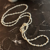 Long white beaded pearl necklace styled in gentle loops, ideal for layering or solo wear.