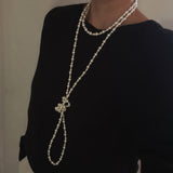 Long white beaded pearl necklace styled in gentle loops, ideal for layering or solo wear.