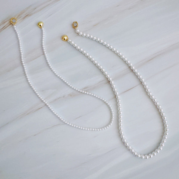 Set of two versatile pearl necklaces featuring luminous pearls in varying sizes, designed with magnetic clasps for easy wear and styling; can be worn individually or linked together for a longer layered look.