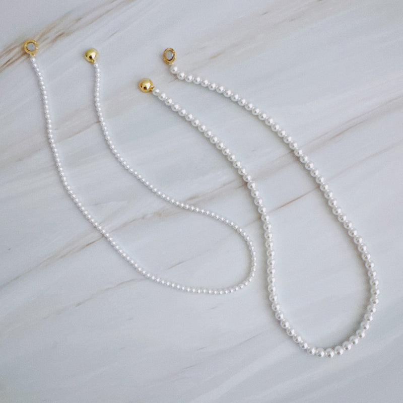 Set of two versatile pearl necklaces featuring luminous pearls in varying sizes, designed with magnetic clasps for easy wear and styling; can be worn individually or linked together for a longer layered look.