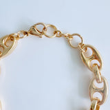 Gold-tone bracelet featuring a twisted, horse-bit-inspired design with interlocking links, offering an elegant equestrian flair and flexible fit.