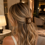 Woman with long, wavy hair wearing a leopard print hair clip indoors.