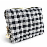 Gingham quilted cosmetic case in black with gold daisy zipper pull in white background
