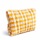 Gingham quilted cosmetic case in light orange with gold daisy zipper pull in white background