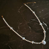 Gold-tone chain necklace featuring a mix of small polished pearls and irregular freshwater-style pearls, finished with an adjustable clasp closure.