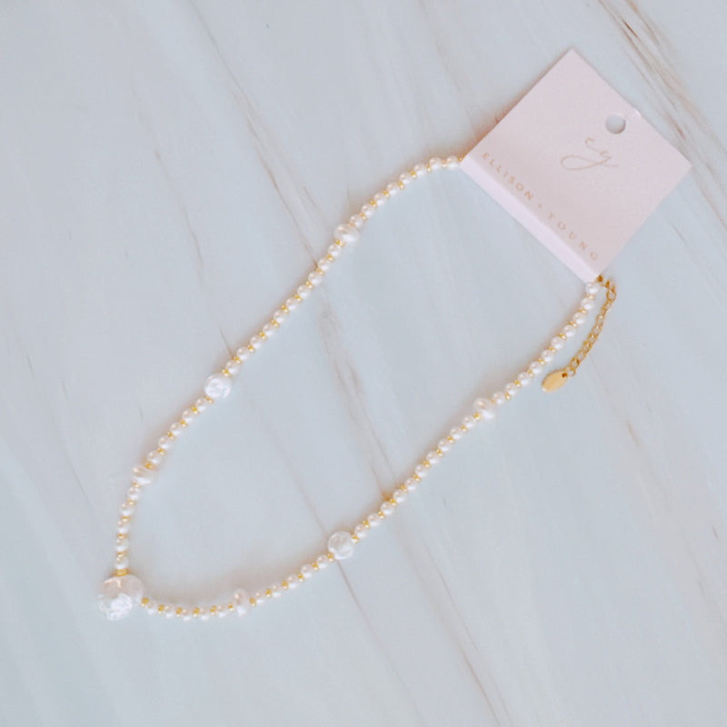 Gold-tone chain necklace featuring a mix of small polished pearls and irregular freshwater-style pearls, finished with an adjustable clasp closure.
