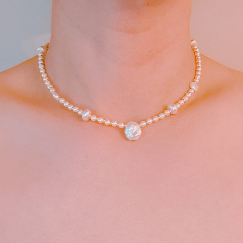 Gold-tone chain necklace featuring a mix of small polished pearls and irregular freshwater-style pearls, finished with an adjustable clasp closure.