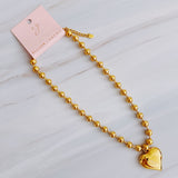Gold-toned necklace featuring a chunky beaded chain and a bold puffed heart pendant, creating a striking statement piece with vintage flair.