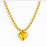 Gold-toned necklace featuring a chunky beaded chain and a bold puffed heart pendant, creating a striking statement piece with vintage flair.