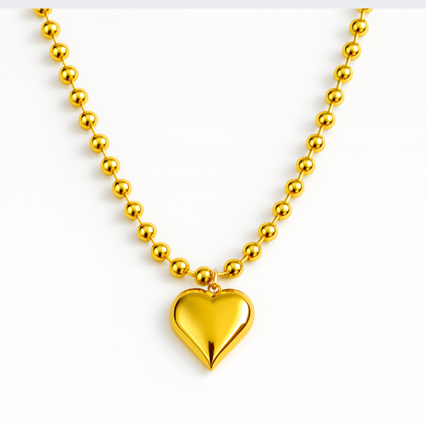 Gold-toned necklace featuring a chunky beaded chain and a bold puffed heart pendant, creating a striking statement piece with vintage flair.