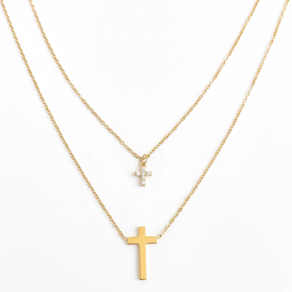 Gold-toned layered necklace featuring two sleek cross pendants, one on each tier of delicate chain links for a modern, faith-inspired design.