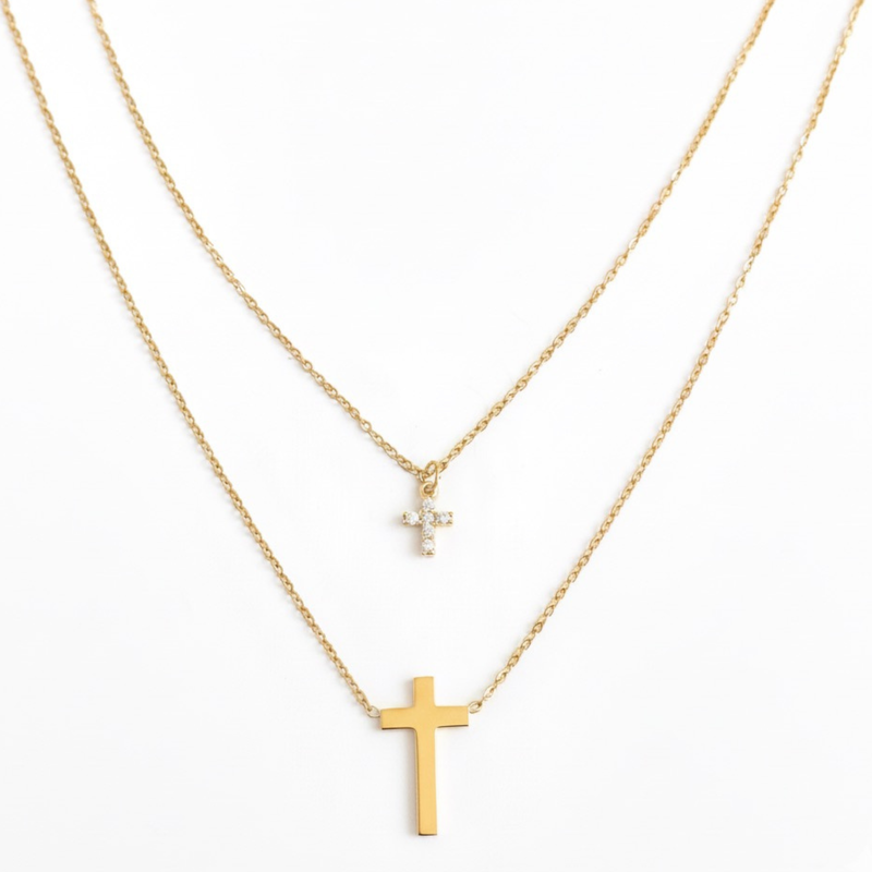 Gold-toned layered necklace featuring two sleek cross pendants, one on each tier of delicate chain links for a modern, faith-inspired design.