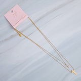 Gold-toned layered necklace featuring two sleek cross pendants, one on each tier of delicate chain links for a modern, faith-inspired design.