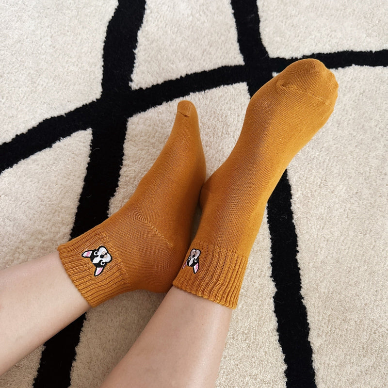 Two pairs of ankle-length socks featuring playful embroidered French bulldog designs near the ankle. The set includes one pair in a solid neutral tone and another in a subtle contrast color, both crafted from soft, comfortable fabric.