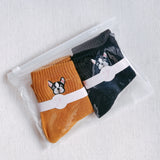 Two pairs of ankle-length socks featuring playful embroidered French bulldog designs near the ankle. The set includes one pair in a solid neutral tone and another in a subtle contrast color, both crafted from soft, comfortable fabric.
