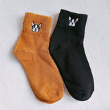 Two pairs of ankle-length socks featuring playful embroidered French bulldog designs near the ankle. The set includes one pair in a solid neutral tone and another in a subtle contrast color, both crafted from soft, comfortable fabric.