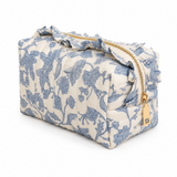 a blue floral toile print cosmetic case with gold zipper, matching fabric ruffle details on top around zipper