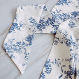 Elegant and versatile long silk hair scarf featuring a classic French toile pattern. The French Toile Sleek and Long Hair Scarf adds a touch of Parisian charm, perfect for tying around a ponytail, wrapping around a bun, or styling as a headband.