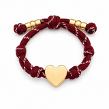 a burgundy rope bracelet with gold heart charm on the white background
