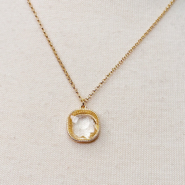 Gold chain necklace featuring a cushion-cut clear crystal pendant with a textured gold bezel, radiating timeless shine and elegance.