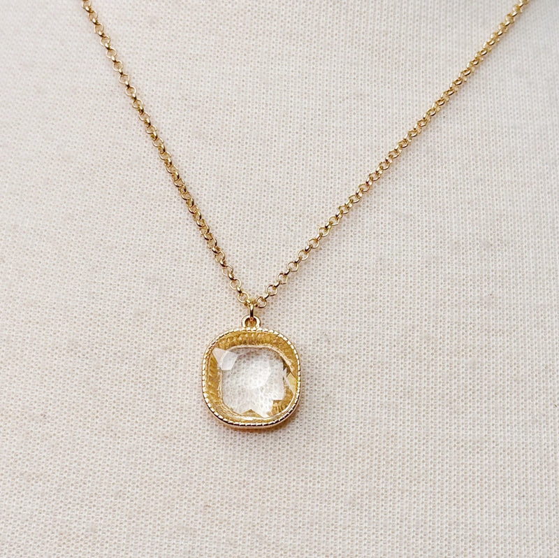 Gold chain necklace featuring a cushion-cut clear crystal pendant with a textured gold bezel, radiating timeless shine and elegance.