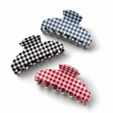 Three gingham checkered hair clips in black, white, and red on a white background