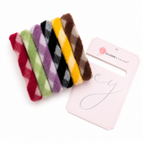 Set of colorful fuzzy hair ties with a branded card on a white background