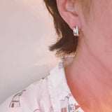 Contoured silver-tone huggie earrings featuring a sleek sculpted shape with a subtle strip of sparkling stones along one edge for a hint of glam.