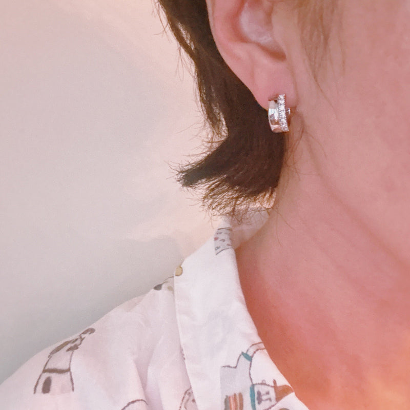 Contoured silver-tone huggie earrings featuring a sleek sculpted shape with a subtle strip of sparkling stones along one edge for a hint of glam.