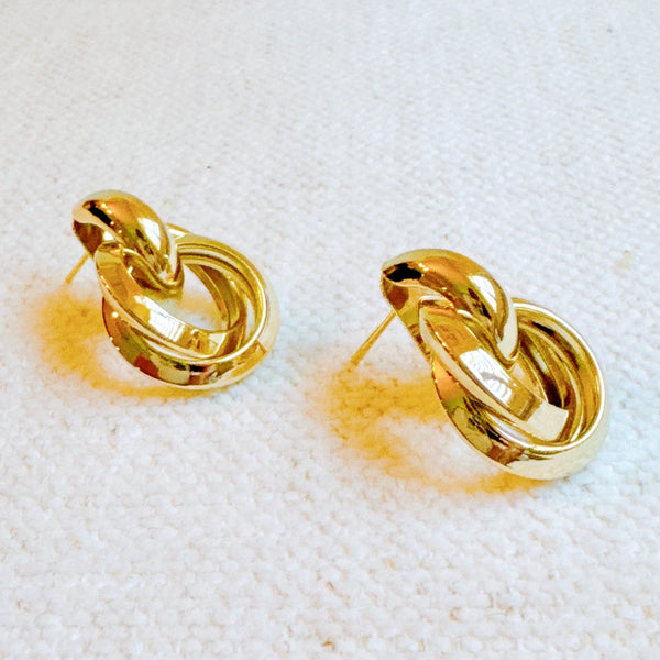 Gold-tone knocker-style earrings with a bold, circular design and a smooth, polished finish for a statement look.