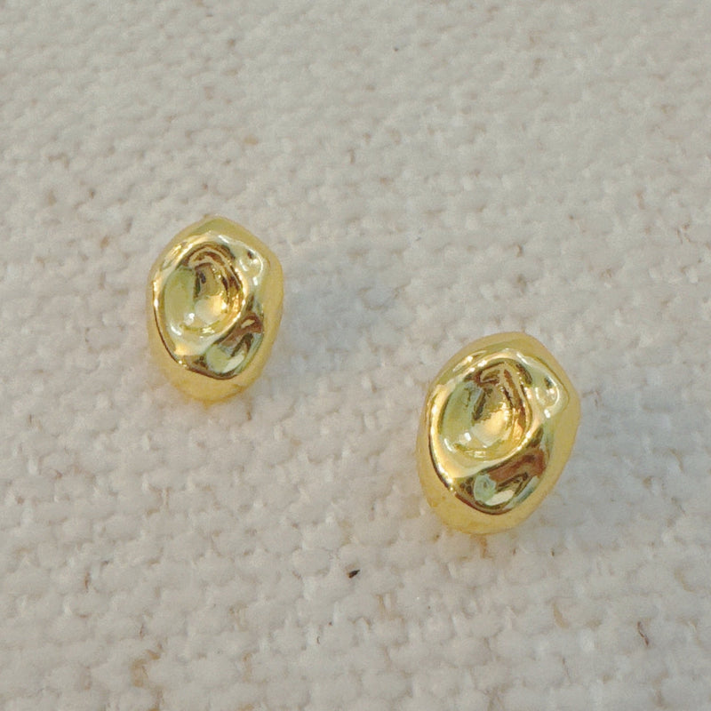 Gold-tone dome stud earrings with a smooth, pebble-like shape and a polished finish for a modern, minimalist look.
