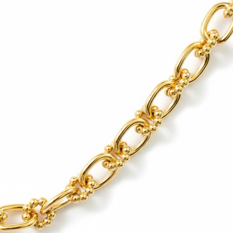 Close-up view of a gold-toned statement necklace featuring oversized oval links adorned with small textured bubble accents for a bold, dimensional look.