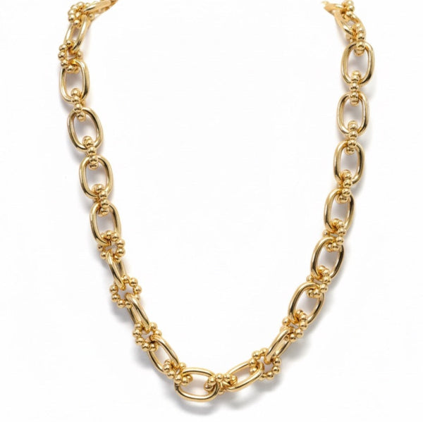 Close-up view of a gold-toned statement necklace featuring oversized oval links adorned with small textured bubble accents for a bold, dimensional look.
