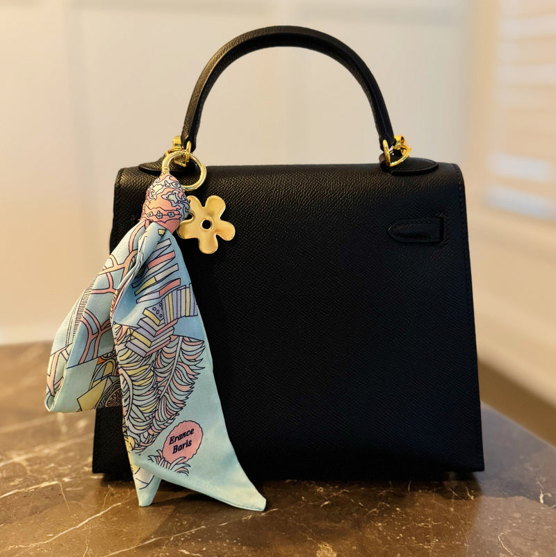 Chic bag charm featuring a flowing printed scarf tied to a gold-tone chain with assorted golden charms for a luxe, fashion-forward accessory