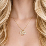 Elegant gold clover-shaped pendant encrusted with shimmering clear crystals. The Golden Clover Crystal Necklace features heart-shaped petals and a radiant gold finish, blending modern charm with timeless sparkle.
