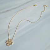 Elegant gold clover-shaped pendant encrusted with shimmering clear crystals. The Golden Clover Crystal Necklace features heart-shaped petals and a radiant gold finish, blending modern charm with timeless sparkle.