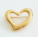Shiny gold-tone heart-shaped brooch pin with fluid, sculptural lines and a modern artistic silhouette—perfect as a statement accent on jackets, scarves, or bags.