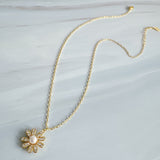 Gold-tone necklace featuring a daisy-inspired pendant with a luminous pearl center surrounded by sparkling crystal-studded petals. The design blends classic elegance with a fresh, feminine touch, perfect for layering or wearing solo.