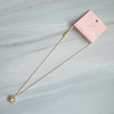 Gold-tone necklace featuring a daisy-inspired pendant with a luminous pearl center surrounded by sparkling crystal-studded petals. The design blends classic elegance with a fresh, feminine touch, perfect for layering or wearing solo.