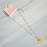 Close-up of a gold-tone heart-shaped pendant necklace engraved with the word “MAMA.” The pendant features radiant sunburst detailing and a polished finish, creating a luminous and heartfelt design that symbolizes warmth and love