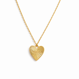 Close-up of a gold-tone heart-shaped pendant necklace engraved with the word “MAMA.” The pendant features radiant sunburst detailing and a polished finish, creating a luminous and heartfelt design that symbolizes warmth and love