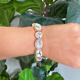 Golden stretch bracelet featuring faceted glass stones in varying shapes, set in a polished gold-tone frame. The elastic design ensures a comfortable fit while showcasing subtle sparkle and refined elegance. Perfect for stacking or wearing solo for a chic touch.