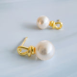 Elegant pearl drop earrings featuring smooth white pearls suspended from sculpted gold loops. The design blends modern artistry with timeless sophistication, creating a refined accessory for everyday or formal wear.