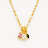 Close-up of a gold paperclip chain necklace featuring an eclectic mix of dangling gem-shaped charms in various cuts and colors, the stones clustered at the center.